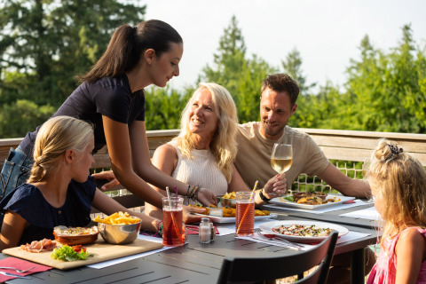 Una familia disfruta de una comida al aire libre en Camping Le Sequoia, un parque de vacaciones en Nouvelle-Aquitaine, Francia.