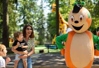 Gezin geniet van ontmoeting met mascotte op Camping Le Sequoia, vakantiepark in Nouvelle-Aquitaine, Frankrijk.