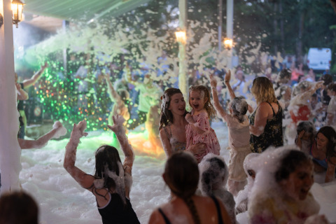 Niños y adultos se divierten bailando en espuma durante una fiesta en Camping Le Sequoia, Nouvelle-Aquitaine, Francia.