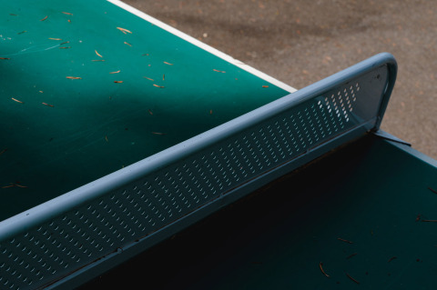 Outdoor table tennis table with metal net and pine needles, at Camping Le Sequoia, Nouvelle-Aquitaine, France.