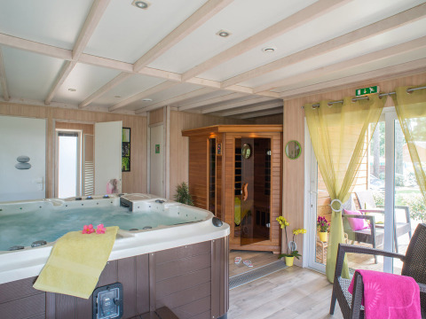 Zona de spa interior en Camping Le Sequoia, Nouvelle-Aquitaine, Francia, con jacuzzi, sauna y terraza.