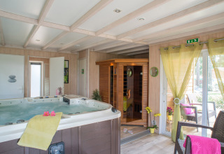 Indendørs spa-område på Camping Le Sequoia i Nouvelle-Aquitaine med jacuzzi, sauna og terrasseområde.