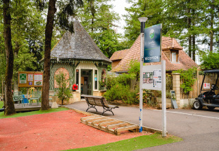 Receptie bij Camping Le Sequoia vakantiepark in Nouvelle-Aquitaine, Frankrijk, met bomen en bankjes.