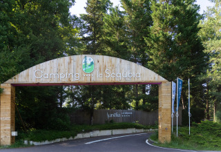 Houten toegangspoort van Camping Le Sequoia vakantiepark, omringd door bomen in Nouvelle-Aquitaine, Frankrijk.