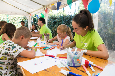 Children and staff doing crafts and drawing together at Camping Leï Suves holiday park in southern France.