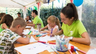 Niños y monitores haciendo manualidades y dibujando en el parque vacacional Camping Leï Suves, Francia.