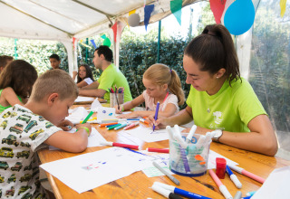 Children and staff doing crafts and drawing together at Camping Leï Suves holiday park in southern France.