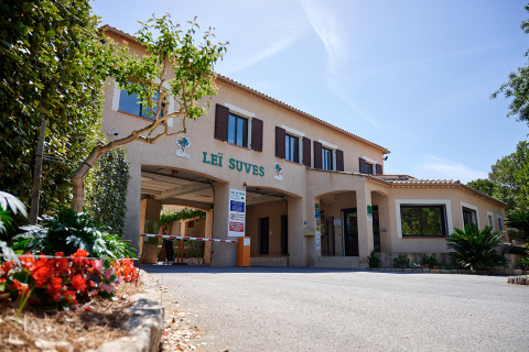 Entrada principal del Camping Leï Suves en Provence-Alpes-Côte d’Azur, Francia, rodeada de plantas y flores.