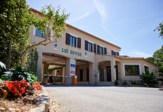 Entrada principal del Camping Leï Suves en Provence-Alpes-Côte d’Azur, Francia, rodeada de plantas y flores.