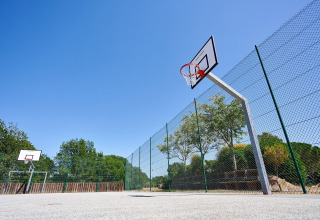Campo da basket all'aperto con recinzione e cielo blu al Camping Leï Suves in Provenza-Alpi-Costa Azzurra, Francia.