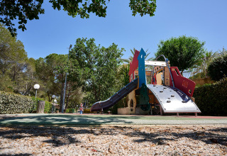 Legeplads med moderne legetårn og rutsjebane omgivet af grønne træer på Camping Leï Suves i Provence.