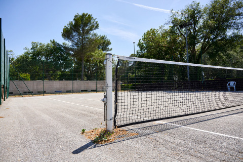 Campo da tennis all’aperto con rete al Camping Leï Suves in Provenza-Alpi-Costa Azzurra, Francia, giornata di sole.