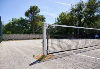 Campo da tennis all’aperto con rete al Camping Leï Suves in Provenza-Alpi-Costa Azzurra, Francia, giornata di sole.