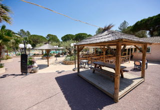 Outdoor seating area with thatched pavilions at Camping Leï Suves in Provence-Alpes-Côte d’Azur, France.