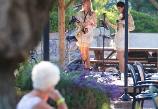 Vrouw kijkt naar een optreden van twee vrouwelijke muzikanten op Camping Leï Suves in de Provence, Frankrijk.