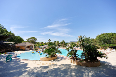 Piscina all'aperto con palme e lettini al Camping Leï Suves in Provenza-Alpi-Costa Azzurra, Francia.