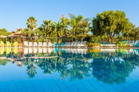 Piscina con tumbonas y palmeras en Camping Leï Suves, un parque vacacional en Provence-Alpes-Côte d’Azur, Francia.