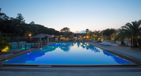 Piscina iluminada al atardecer en Camping Leï Suves, un parque vacacional en Provenza-Alpes-Costa Azul, Francia.