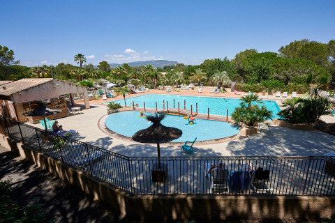 Gran piscina en el Camping Leï Suves, un parque vacacional en Provenza-Alpes-Costa Azul, Francia, rodeado de vegetación.