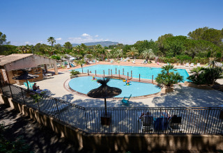 Gran piscina en el Camping Leï Suves, un parque vacacional en Provenza-Alpes-Costa Azul, Francia, rodeado de vegetación.