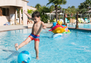 Bambino calcia una palla in piscina presso Camping Leï Suves, Provenza-Alpi-Costa Azzurra, Francia.