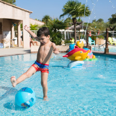 Niño patea una pelota en la piscina de Camping Leï Suves, Provenza-Alpes-Costa Azul, Francia.