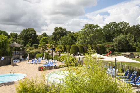 Vista su piscine, lettini e giardino rigoglioso al Camping Les Bois du Bardelet, Centro-Valle della Loira, Francia.