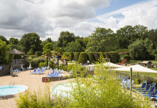 Vista su piscine, lettini e giardino rigoglioso al Camping Les Bois du Bardelet, Centro-Valle della Loira, Francia.