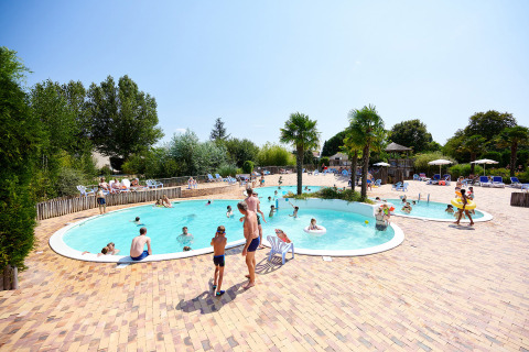 Familias disfrutan de un día soleado en la piscina al aire libre de Camping Les Bois du Bardelet, Centre-Val de Loire, Francia.