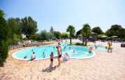 Familier nyder en solrig dag ved udendørs swimmingpoolen på Camping Les Bois du Bardelet i Centre-Val de Loire, Frankrig.