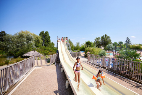 Bambini che si divertono sul doppio scivolo d'acqua al Camping Les Bois du Bardelet, Centre-Val de Loire, Francia.