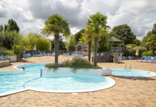Swimmingpool og solsenge ved Camping Les Bois du Bardelet i Centre-Val de Loire, Frankrig, under dramatisk himmel.