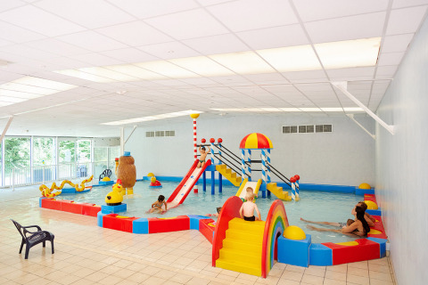 Overdekt kinderzwembad met kleurrijke glijbanen in Camping Les Bois du Bardelet, Centre-Val de Loire, Frankrijk.