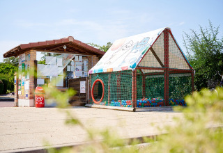 Zona de juegos con piscina de bolas y recepción en Camping Les Bois du Bardelet, Centro-Valle del Loira, Francia.