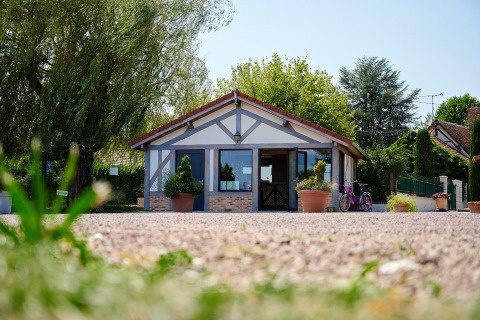 Entrada de Camping Les Bois du Bardelet en Centre-Val de Loire, Francia, con plantas en macetas y bicicleta.