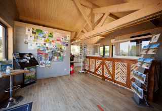 Rezeption im Camping Les Bois du Bardelet in Centre-Val de Loire, Frankreich, mit Flyern und Infotafel.