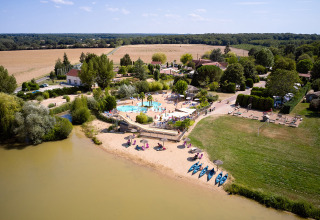 Vue aérienne du Camping Les Bois du Bardelet avec piscine, plage, kayaks et cadre verdoyant en France.