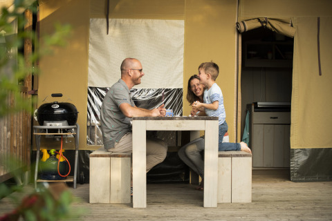 Une famille passe un bon moment devant leur cabane au Camping Les Bois du Bardelet, Centre-Val de Loire, France.