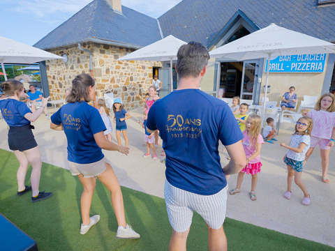 Children join outdoor activities with staff at Camping Les Genêts holiday park in Occitanie, France.