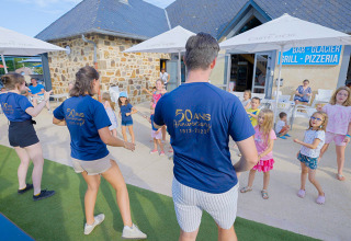 Children join outdoor activities with staff at Camping Les Genêts holiday park in Occitanie, France.