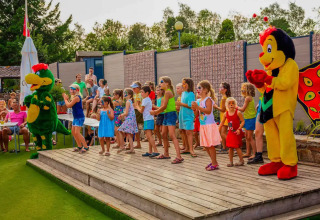 Bambini che partecipano a uno spettacolo con mascotte al Camping Les Genêts in Occitania, Francia.