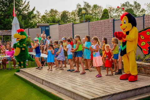 Kinderen dansen en spelen met mascottes op het Camping Les Genêts vakantiepark in Occitanië, Frankrijk.