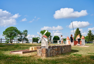 Camping Les Genêts in Occitanie, Frankreich, mit Menschen, Minigolfanlage und malerischer Natur im Freien.