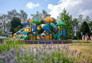 Farverig legeplads med rutsjebaner og legeredskaber på Camping Les Genêts i Occitanie, Frankrig.