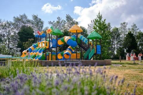 Farverig legeplads med rutsjebaner og legeredskaber på Camping Les Genêts i Occitanie, Frankrig.