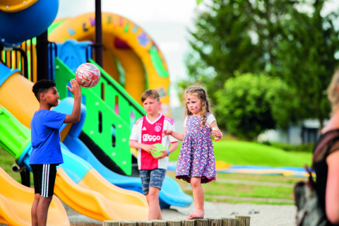 Niños jugando en un colorido parque infantil en Camping Les Genêts, un parque vacacional en Occitania, Francia.