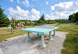 Udendørs bordtennisbord og legeplads i holidayparken Camping Les Genêts, Occitanie, Frankrig.