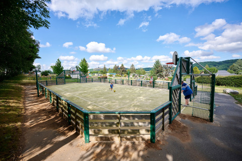 Cancha multideporte en Camping Les Genêts, Occitania, Francia, con niños jugando y cielo despejado.