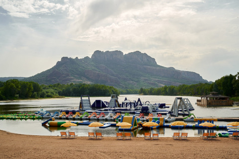 Inflatable water park on a lake with mountains in the background at Camping Les Pêcheurs in southern France.