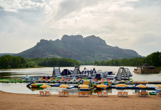 Inflatable water park on a lake with mountains in the background at Camping Les Pêcheurs in southern France.